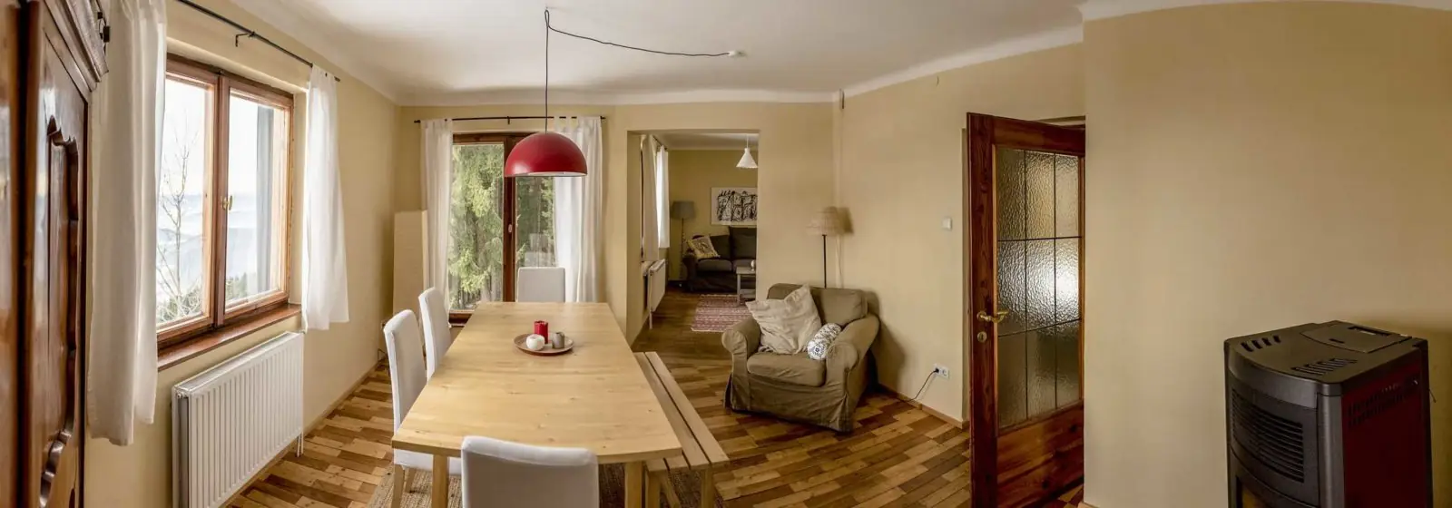 Wohn- und Essbereich des Almhauses mit Holztisch und Kaminofen