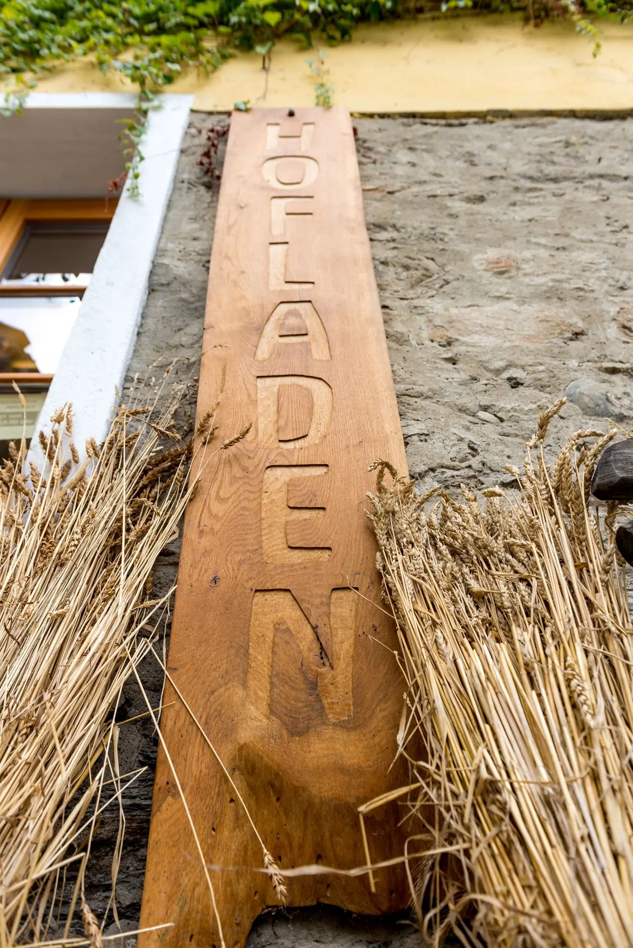 Cartello di legno “Hofladen” (negozio della fattoria) tra covoni di grano