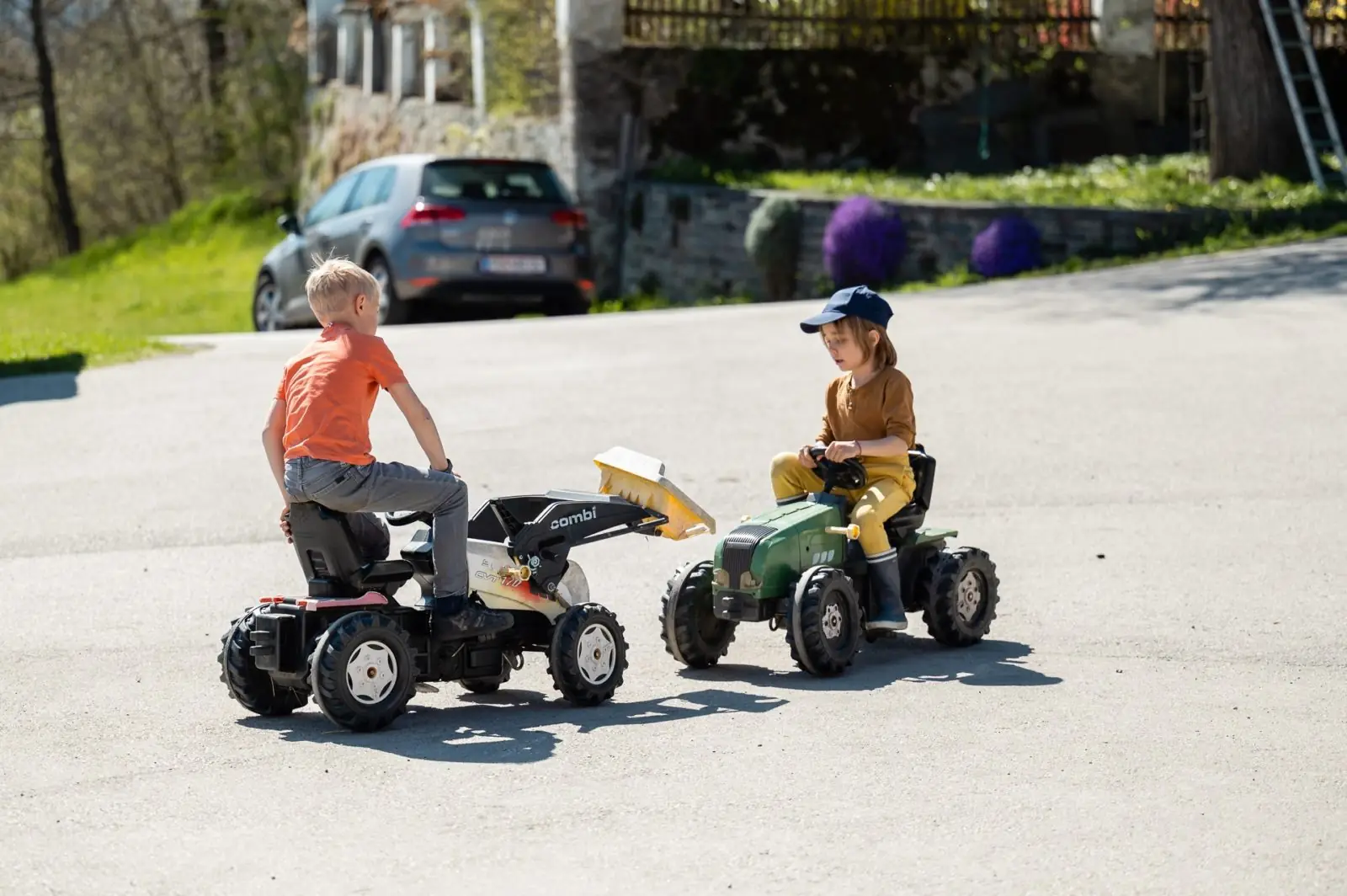 Children on pedal tractors in the farmyard