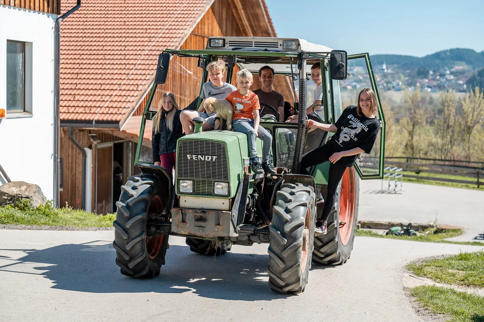 Familie auf dem Traktor am Bauernhof