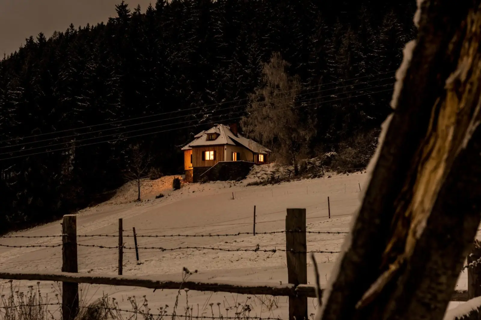 Das beleuchtete Almhaus am Winterabend